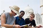 Drei junge Männer betrachten ein Guidebook, Taj Mahal, Agra, Uttar Pradesh, Indien