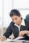 Businesswoman sitting and looking at a notebook in an office
