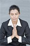 Businesswoman meditating in prayer position
