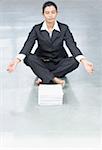 Businesswoman doing yoga in front of a stack of papers