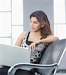 Young woman sitting on a chair with a laptop on her lap