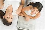 High angle view of a girl using a laptop on the bed beside her mother