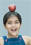 Portrait of a girl balancing an apple on her head