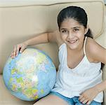 Portrait d'une jeune fille assise dans un fauteuil avec un globe et souriant