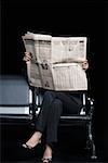 Vue en coupe basse d'une femme d'affaires assis sur un banc et lire un journal