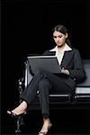 Femme d'affaires assis sur un banc et à l'aide d'un ordinateur portable