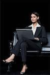 Portrait d'une femme d'affaires assis sur un banc et à l'aide d'un ordinateur portable
