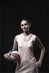 Portrait of a young woman standing and holding a volleyball