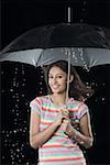 Portrait d'une jeune femme s'abritant sous un parapluie