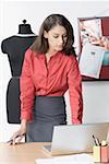 Female fashion designer standing and using a laptop