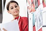 Portrait of a young woman beside a mood board and smirking