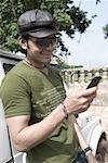 Gros plan d'un texte de jeune homme avec un téléphone mobile de messagerie et souriant, Goa, Inde