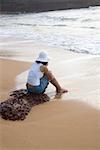 Rear view of a young woman sitting on the beach, Goa, India