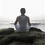 Rear view of a young man doing yoga on the beach, Goa, India