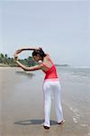 Rear view of a young woman exercising on the beach