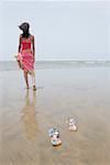 Vue arrière d'une jeune femme marchant sur la plage