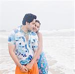 Jeune femme embrassant un jeune homme par derrière sur la plage