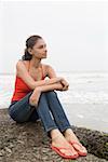 Jeune femme assise sur un rocher et pensée