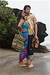 Young man standing with his arm around a young woman on the beach