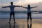 Rear view of a young couple standing on the beach with holding each other's hands