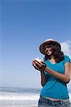 Jeune femme debout sur la plage et tenant une conque