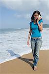 Junge Frau hält einer Muschelschale an ihr Ohr und Wandern am Strand