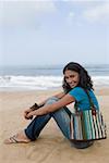Porträt einer jungen Frau am Strand sitzen und Lächeln
