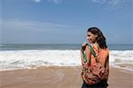 Rear view of a young woman carrying a shoulder bag on the beach