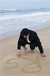 Businessman writing in sand on the beach