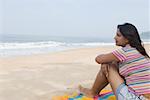 Side profile of a young woman sitting on the beach