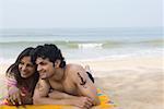 Jeune couple allongé sur la plage et souriant