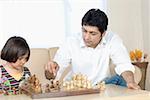 Mid adult man playing chess with his daughter