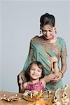 Young woman with her daughter preparing for pooja