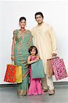 Mid adult man and a young woman with their daughter standing with shopping bags