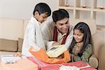 Young man opening a gift in front of his children