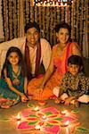 Young couple sitting with their children in front of rangoli