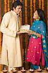 Side profile of a mid adult man and a young woman holding a box of sweets