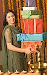 Portrait d'une jeune femme tenant une pile de cadeaux diwali et souriant