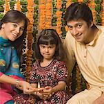 Portrait of a couple sitting with their daughter behind oil lamps and smiling