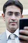 Close-up of a businessman text messaging on a mobile phone