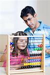 Mid adult man teaching his daughter with an abacus