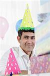 Portrait of a mid adult man wearing a birthday hat and smiling