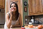 Nahaufnahme einer jungen Frau, die ein schnurloses Telefon in einer Küche im Gespräch