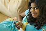 Portrait d'une jeune femme tenant un téléphone mobile sur un canapé