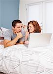 Couple sur le lit avec ordinateur portable