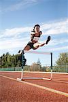 Woman Jumping over Track Hurdle