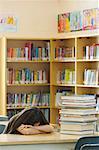 Student in Library Surrounded by Stack of Books