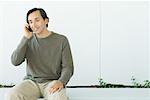 Man sitting, using cell phone, smiling, looking down