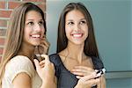 Teenage twin sisters listening to mp3 player together, both smiling and looking up