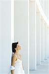 Woman leaning against column, eyes closed, hair tousled by breeze